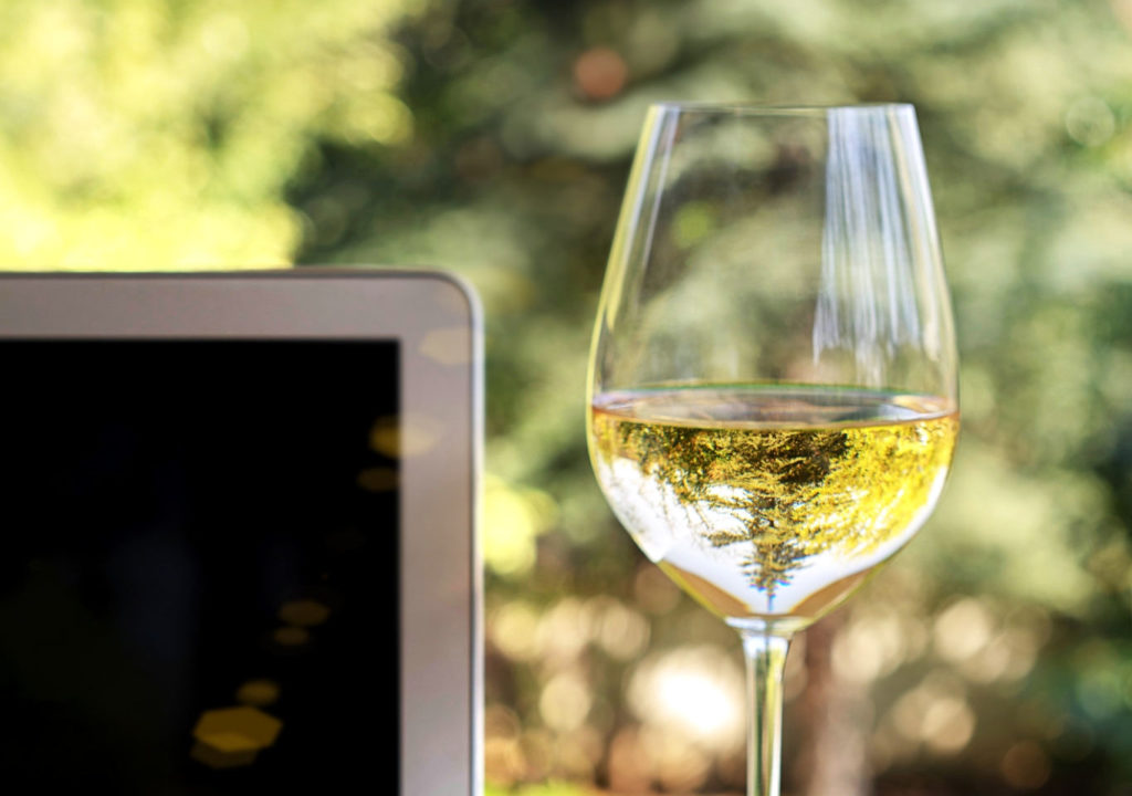 écran d'ordinateur et verre de vin blanc